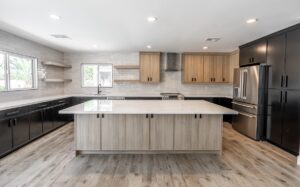 Modern kitchen remodeling with a large island, wood and black cabinets, stainless steel appliances, tile backsplash, floating shelves, and wood-look flooring.