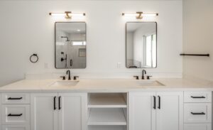 Modern bathroom with double sinks, white cabinets, black fixtures, two rectangular mirrors, and wall-mounted lights above each mirror.
