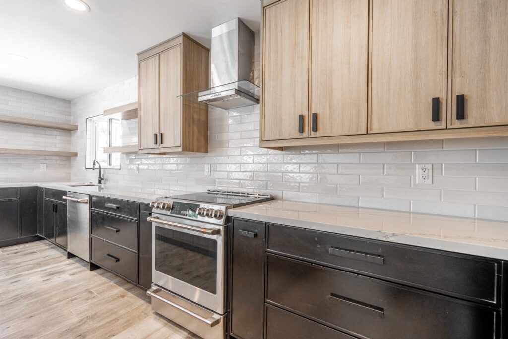 modern kitchen with stainless steel appliances, wood and black cabinetry, white tile backsplash, open shelving, and light wood flooring.